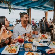 man and woman sitting on chair in front of table with food on top